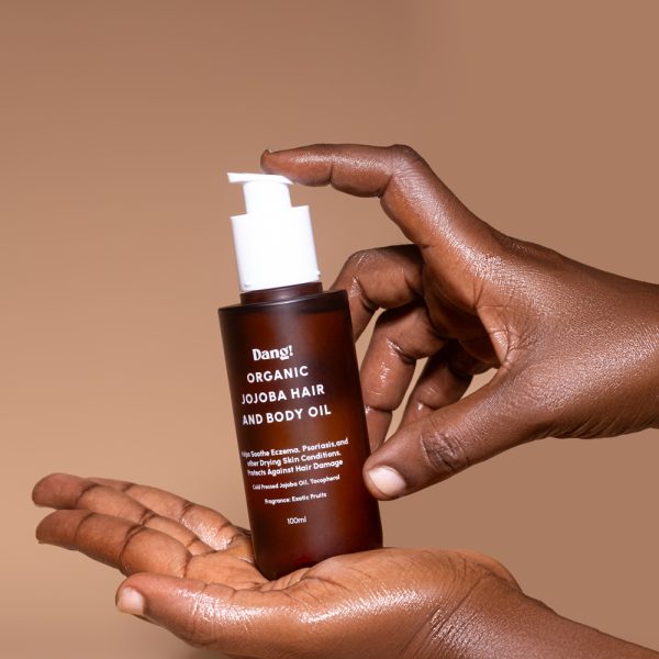 Hands holding a bottle of jojoba oil