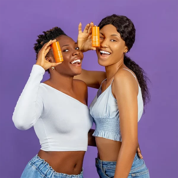 2 ladies holding a bottle of concentrated vitamin C serum