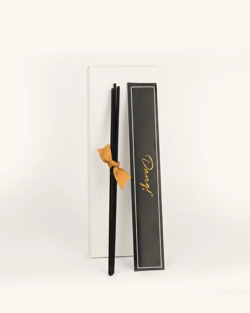 An image of black reed sticks againsts a cream background