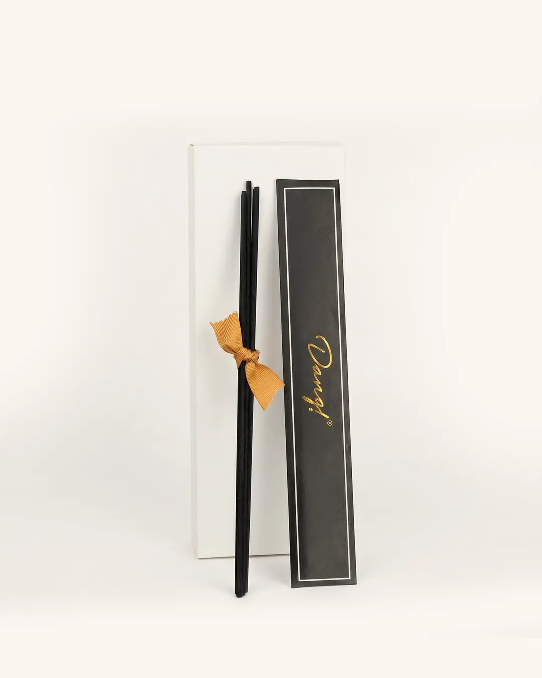 An image of black reed sticks againsts a cream background