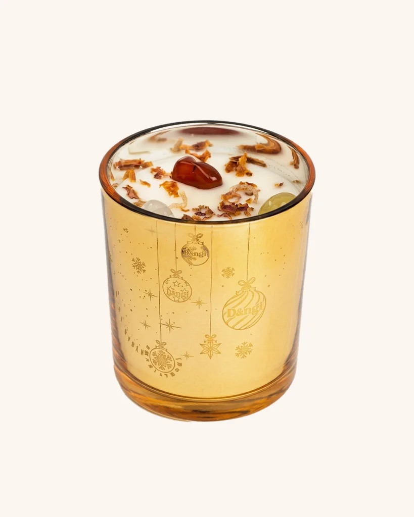 A golden jar of scented candle placed in front of an off white background
