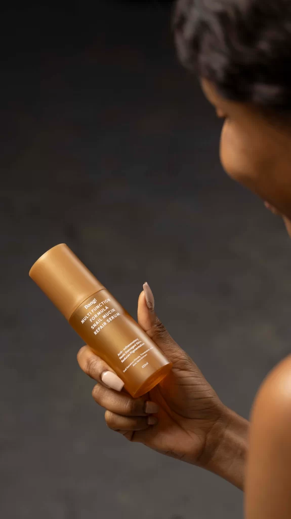 A lady admiring the bottle of snail mucin serum in her hands which offers amazing benefits for the skin