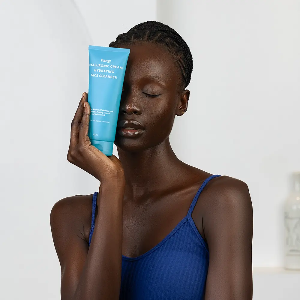 Dark skinned lady holding a face wash formulated with hyaluronic acid