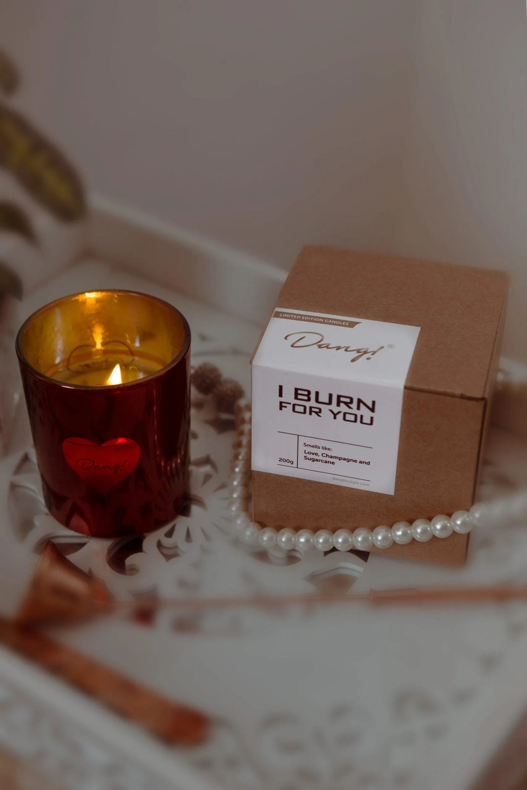 An image of a romantic scented candle lit and placed beside a box