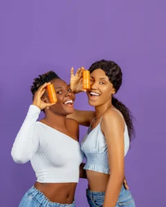 Two ladies holding bottles of serums in their hands which are vitamin C serums for hyperpigmentation