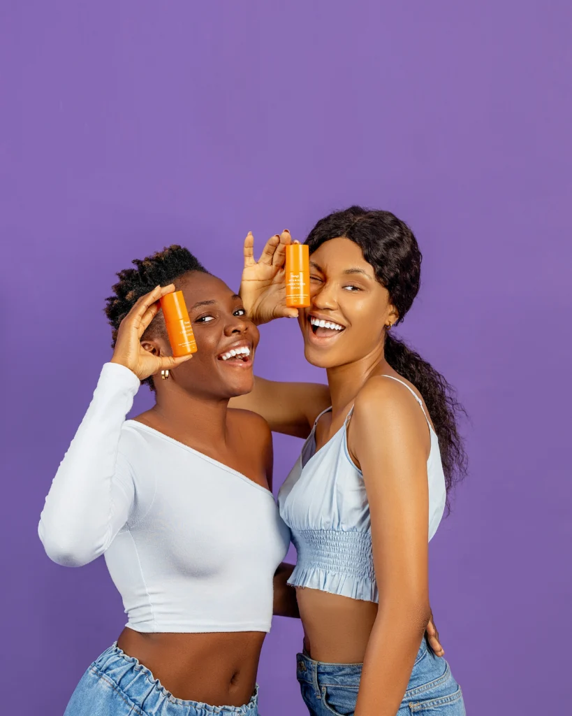 Two ladies holding bottles of serums in their hands which are vitamin C serums for hyperpigmentation