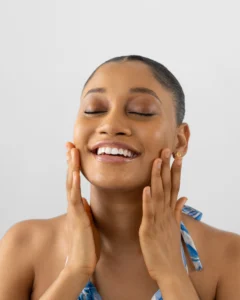 Lady holding smiling and placing her hands on her cheeks showing proper selfcare and positive mental health ideas