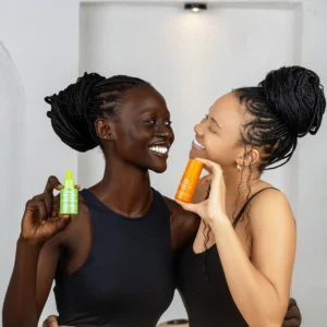 An image of one dark skinned lady and a light skinned lady holding bottles of the best serum for pigmentation in their hands and smiling