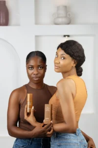 2 models smiling and holding a bottle of serum with tranexamic acid